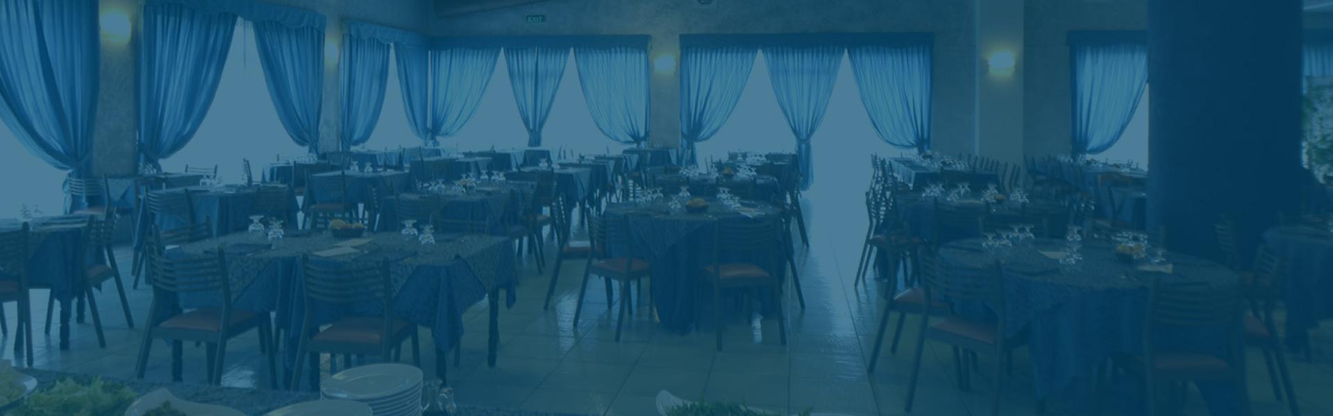 Sala ristorante elegante con tavoli apparecchiati e tende blu.