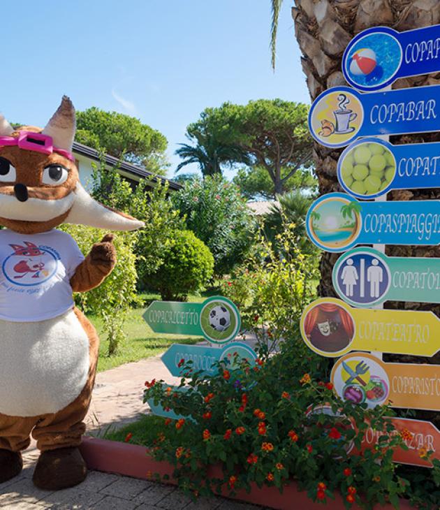 Mascotte accanto a cartelli colorati che indicano diverse attività in un villaggio turistico.