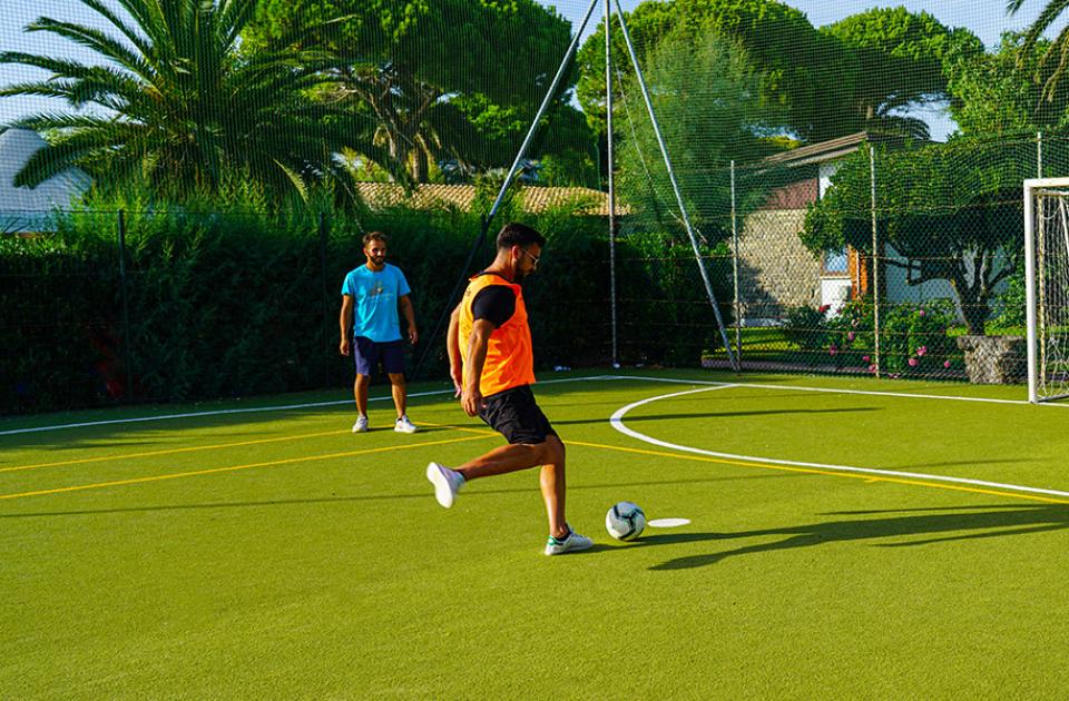 Giocatori di calcetto in azione su un campo all'aperto, uno sta per tirare.