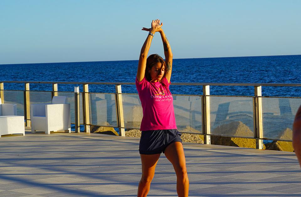 Due persone fanno yoga all'aperto vicino al mare al tramonto.