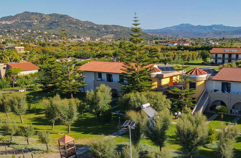 Complesso residenziale immerso nel verde con vista sulle montagne in lontananza.