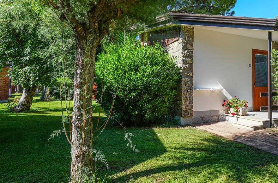 Bungalow immerso nel verde con vialetto e giardino ben curato.