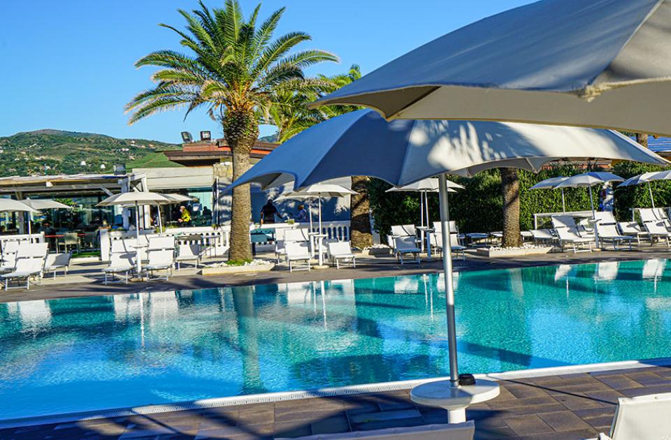 Piscina all'aperto con lettini e ombrelloni, ambiente rilassante e soleggiato.