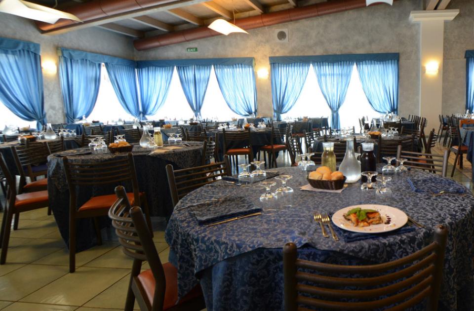 Ristorante elegante con tovaglie blu e piatti raffinati su tavoli apparecchiati.