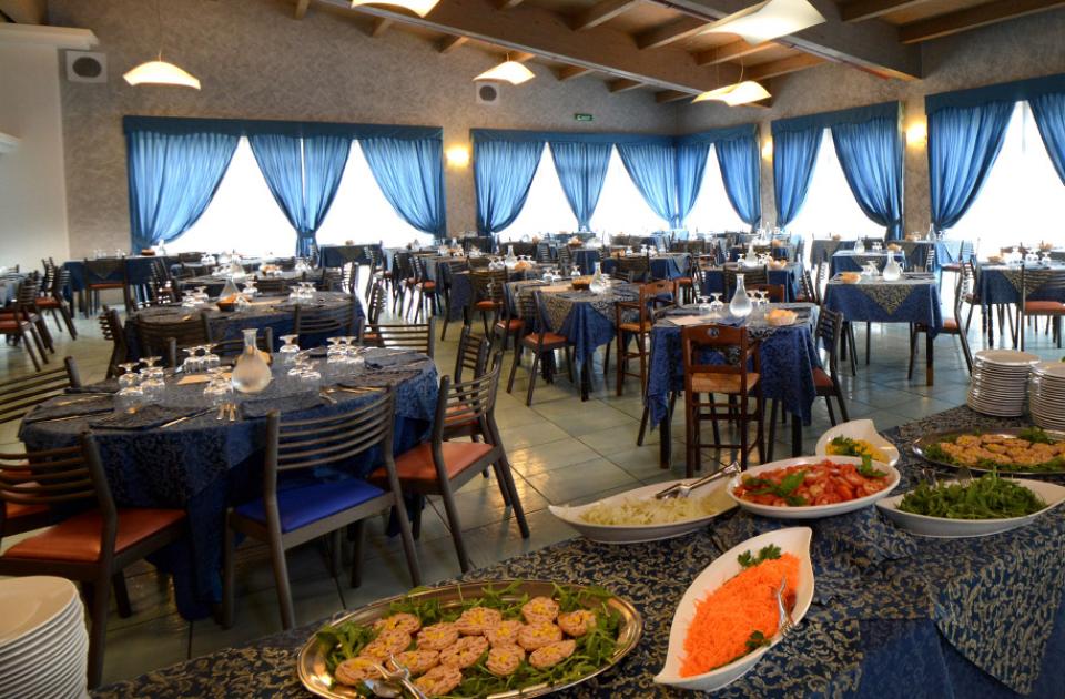 Ristorante elegante con buffet, tavoli apparecchiati e tende blu.