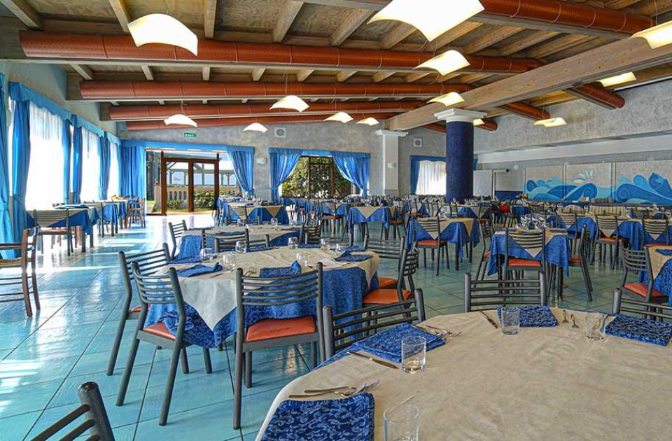 Ristorante elegante con tovaglie blu, ampie finestre e soffitto in legno.