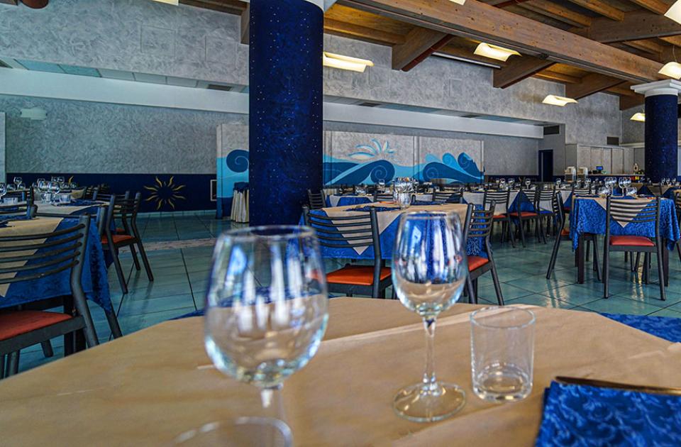 Ristorante elegante con tovaglie blu e bicchieri apparecchiati, atmosfera accogliente e luminosa.